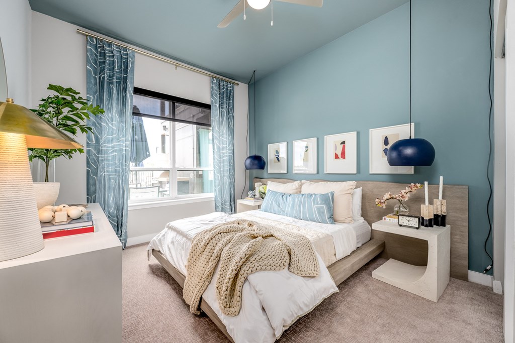 a bedroom with blue walls and a large window with blue curtains at Ironwood Flats, Brandon, Florida