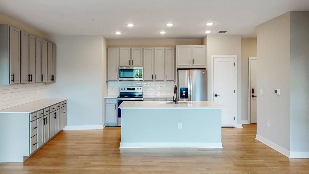 a kitchen with white cabinets and a white island with a sink  at Ironwood Flats, Florida, 33511