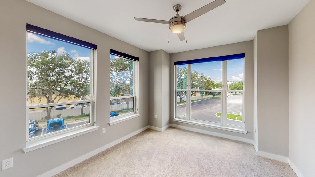 a bedroom with a ceiling fan and large windows at Ironwood Flats, Florida