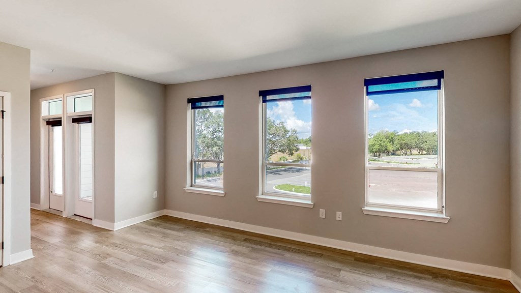 an empty room with hardwood floors and four windows at Ironwood Flats, Florida