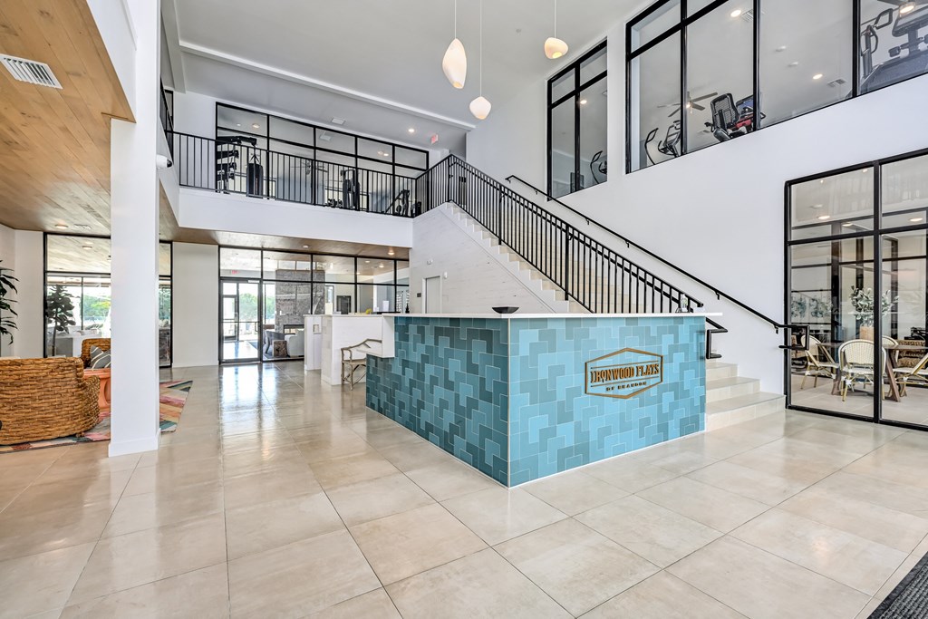 a large lobby with a staircase and a blue tiled reception desk at Ironwood Flats, Brandon, Florida