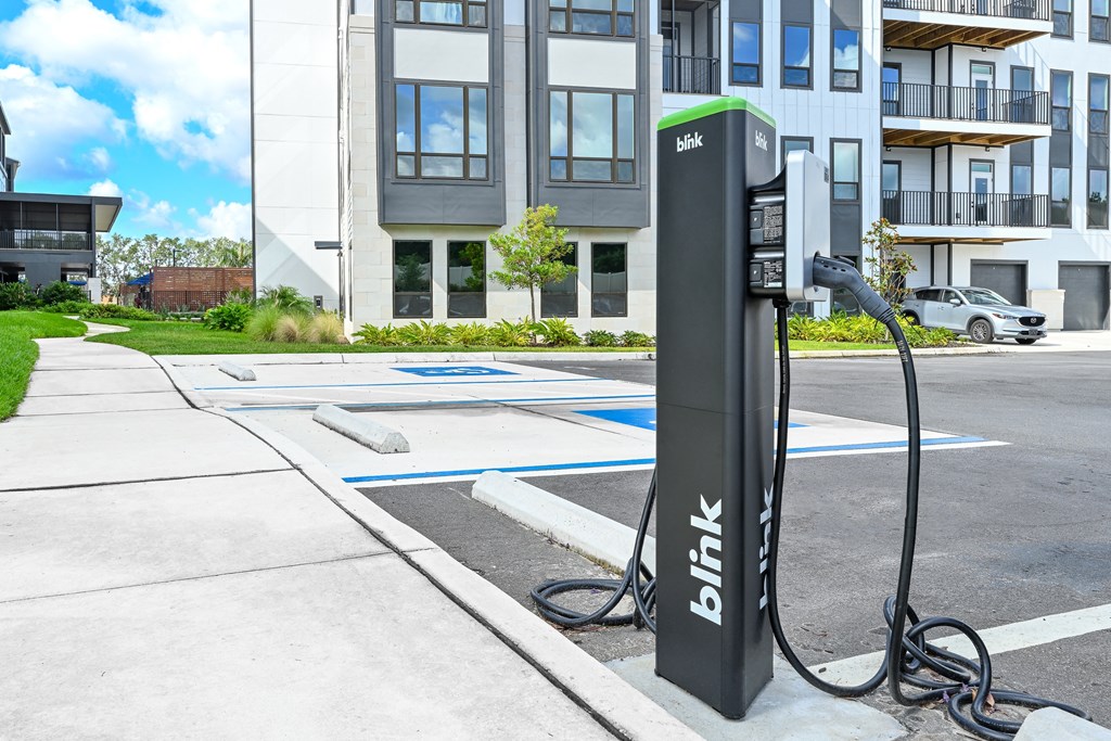 a hybrid electric vehicle plugged into a charging station in front of an apartment building at Ironwood Flats, Brandon
