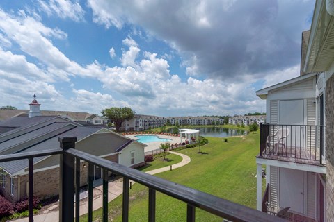 A view from a balcony overlooking a pool and a lake.