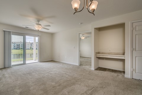 A spacious room with a ceiling fan and a large window with a view of a building outside.