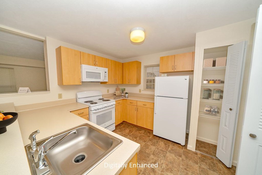 a kitchen with white appliances and wooden cabinets a kitchen with white appliances and wooden cabinets at Limestone Creek Apartment Homes, Madison, AL
