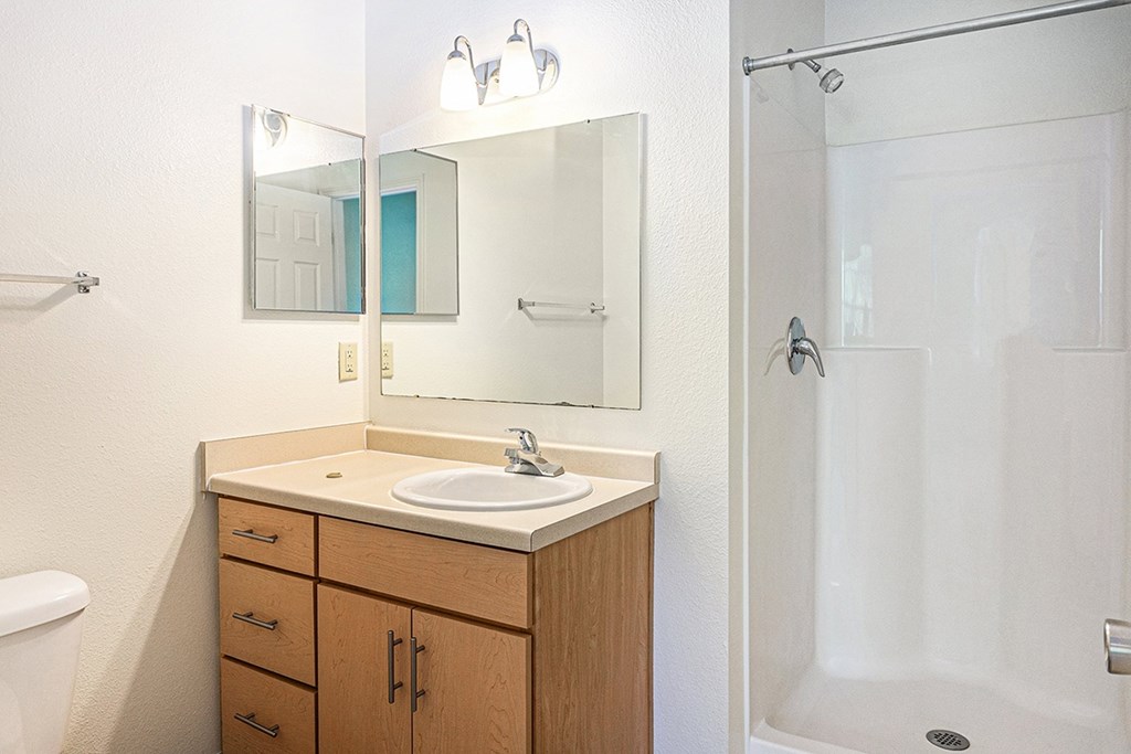 A bathroom with a sink, mirror, and shower at Limestone Creek Apartment Homes, Madison, AL