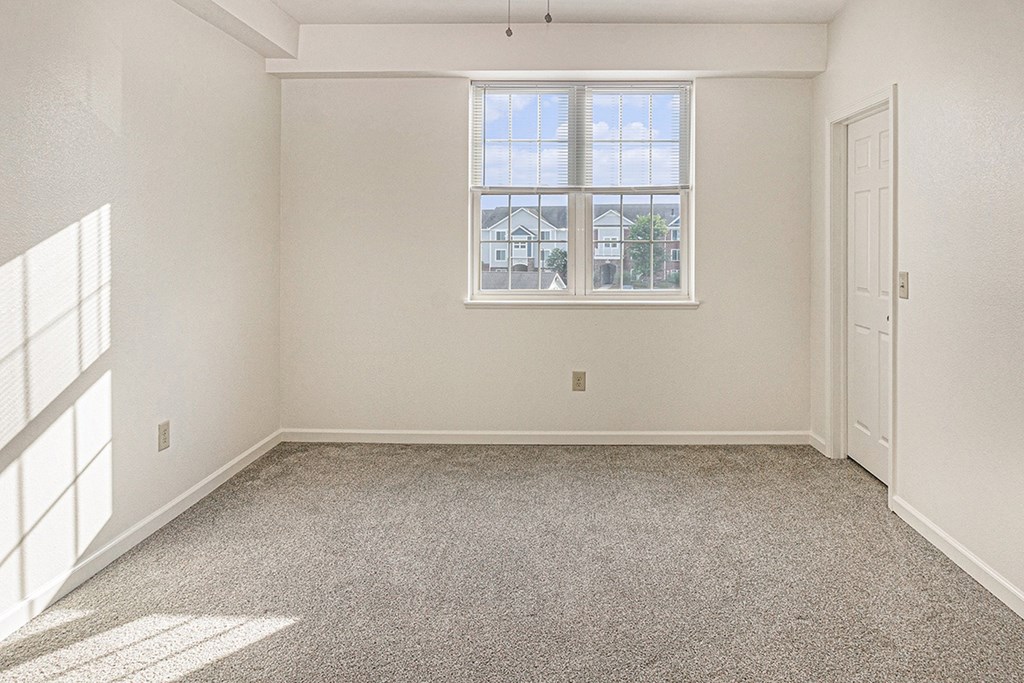 Spacious bedroom with a large window and plush carpet at Limestone Creek Apartment Homes, Alabama