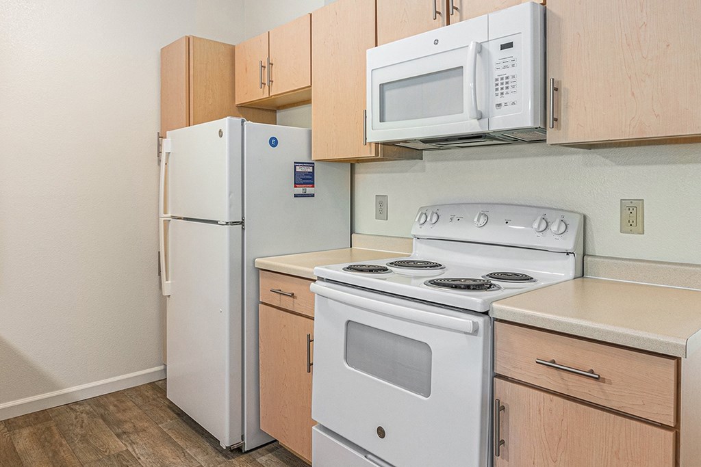 A kitchen with a white refrigerator, stove, and microwave at Limestone Creek Apartment Homes, Madison, AL