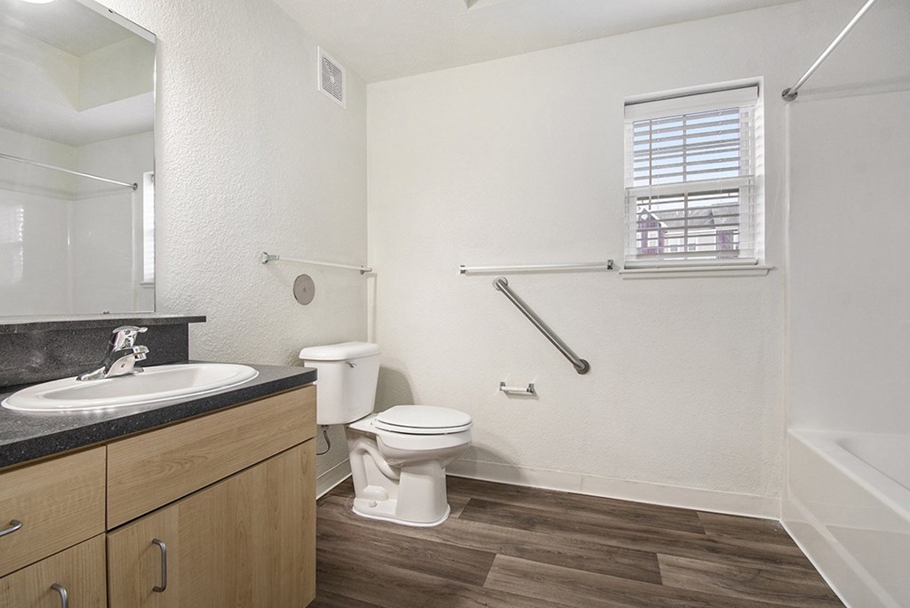 A bathroom with a toilet, sink, and a window at Lynbrook Apartments and Townhomes, Elkhorn, NE, 68022