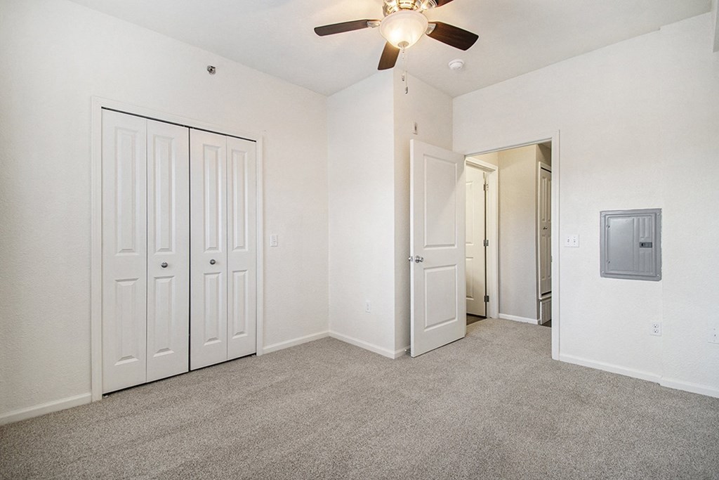 A spacious bedroom with a ceiling fan and a large closet at Lynbrook Apartments and Townhomes, Elkhorn, NE, 68022