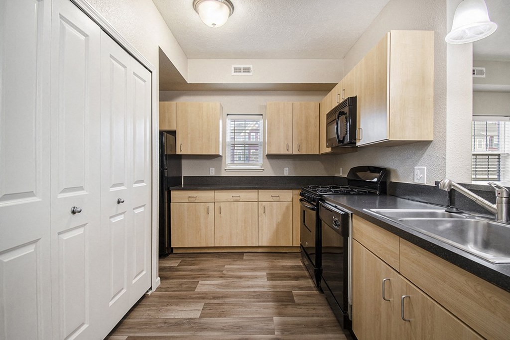 A kitchen with a window, wooden cabinets and black appliances at Lynbrook Apartments and Townhomes, Elkhorn, NE, 68022