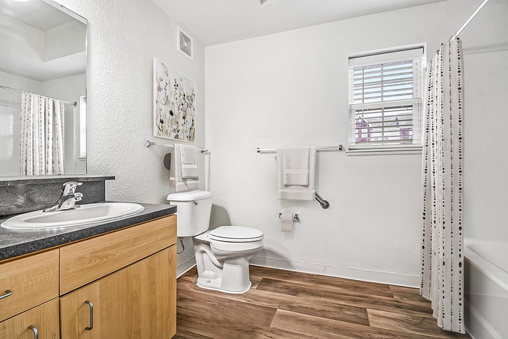 A bathroom with a toilet, sink, and a window at Lynbrook Apartments and Townhomes, Elkhorn, NE, 68022