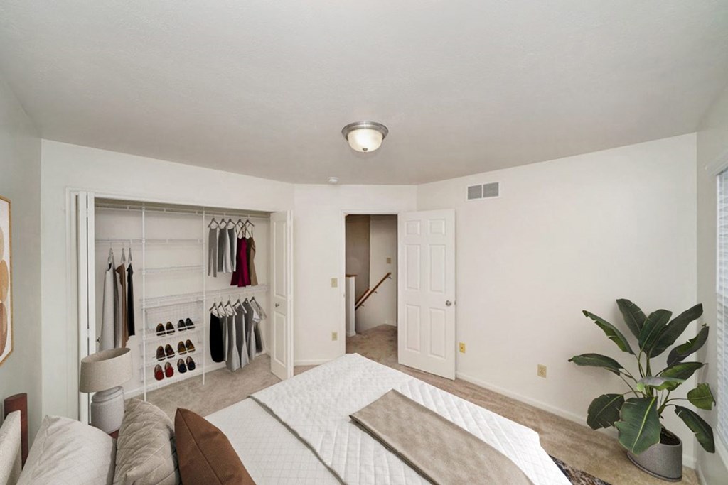 A bedroom with a bed, and a closet with organizers at Lynbrook Apartment Homes and Townhomes, Elkhorn
