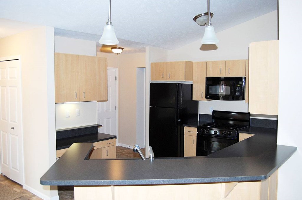 A kitchen with black appliances and a breakfast bar at Lynbrook Apartment Homes and Townhomes, Elkhorn