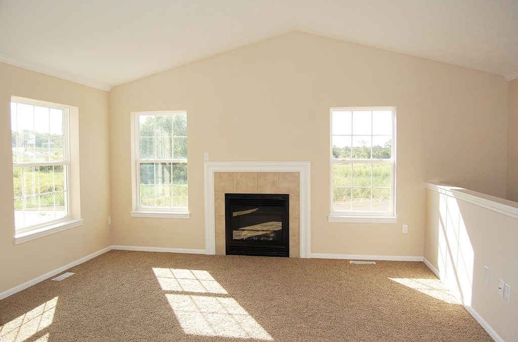 A living room with a fireplace and windows at Lynbrook Apartment Homes and Townhomes, Elkhorn