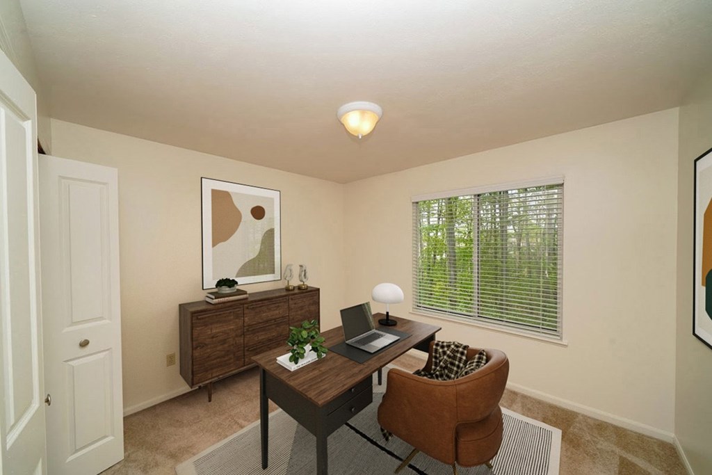 A bedroom with a brown desk with a laptop and a chair at Lynbrook Apartment Homes and Townhomes, Elkhorn