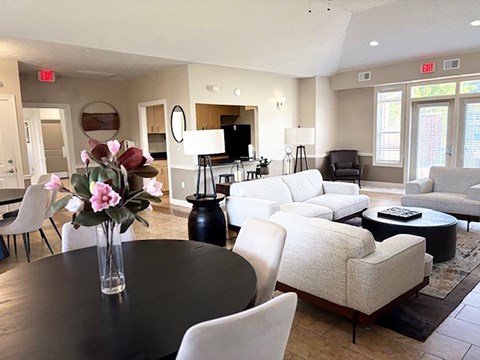 A living room with a round table and white chairs.