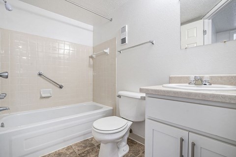 A white toilet sits next to a bathtub in a bathroom at Madeira Apartments, Michigan
