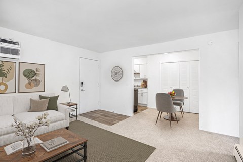A living and dining room with a couch, chair, and a large closet at Madeira Apartments, Kalamazoo, MI