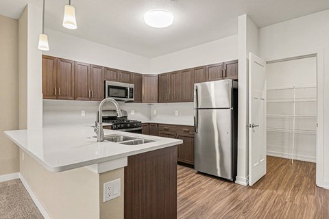 A kitchen with a white counter top and a stainless steel refrigerator.