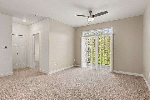 A room with a fan and carpeted floor.