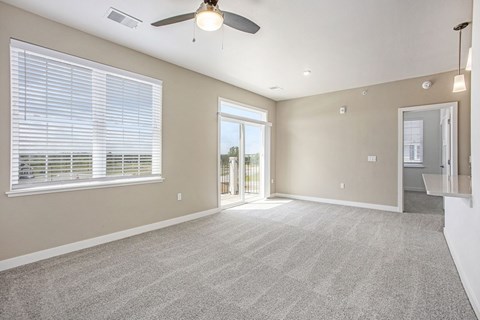 A spacious living room with a 9 foot ceiling, ceiling fan and carpeted floor at Meadowbrooke Apartment Homes in Kentwood, MI 49512