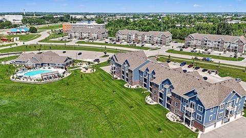 A large grassy area with a swimming pool and apartment buildings.