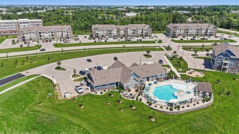 A large house with a pool in the middle of a grassy area.
