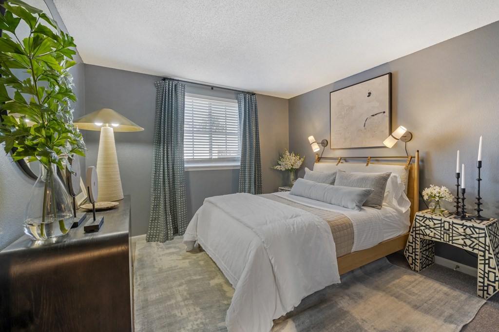 a bedroom with a bed and a dresser in front of a window at Latitudes Apartments, Indianapolis