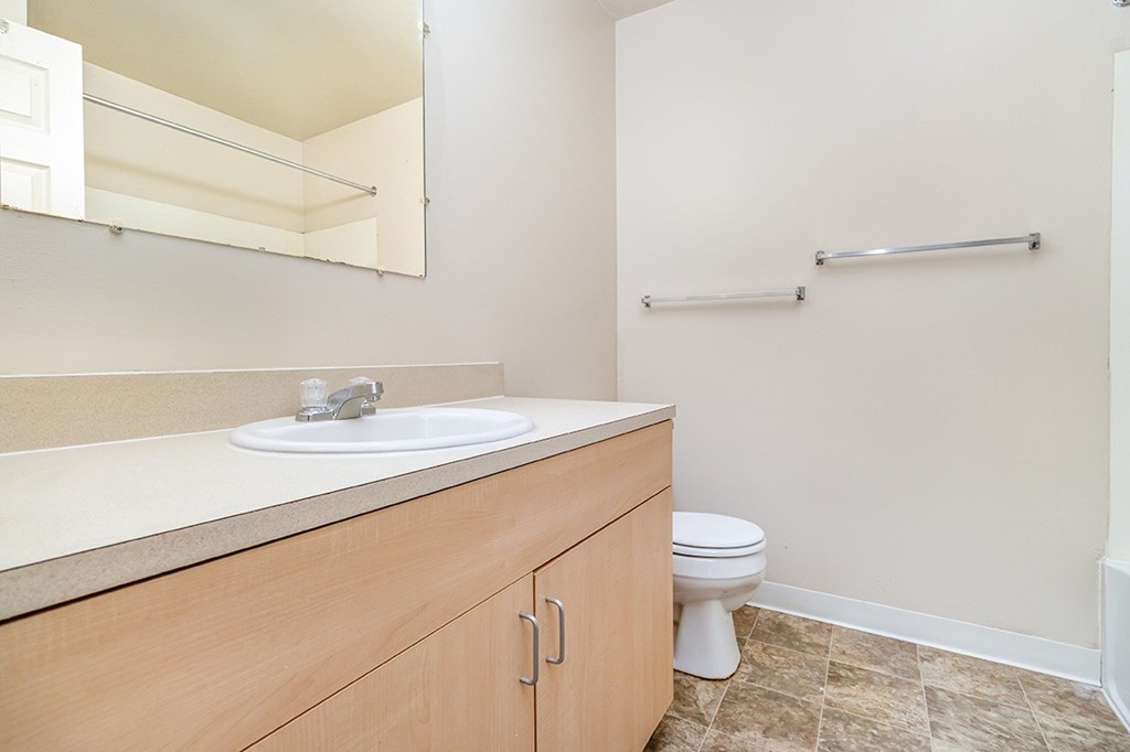 A bathroom with a toilet, sink, and a mirror at Mount Royal Townhomes, Michigan