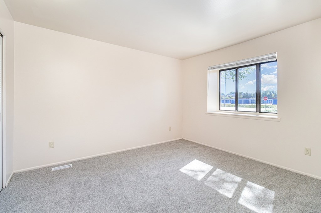A bedroom with a large window and a carpeted floor at Mount Royal Townhomes, Michigan