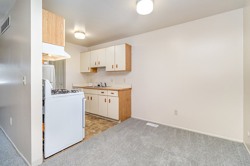 A dining room and kitchen with white appliances and wooden cabinets at Mount Royal Townhomes, Michigan