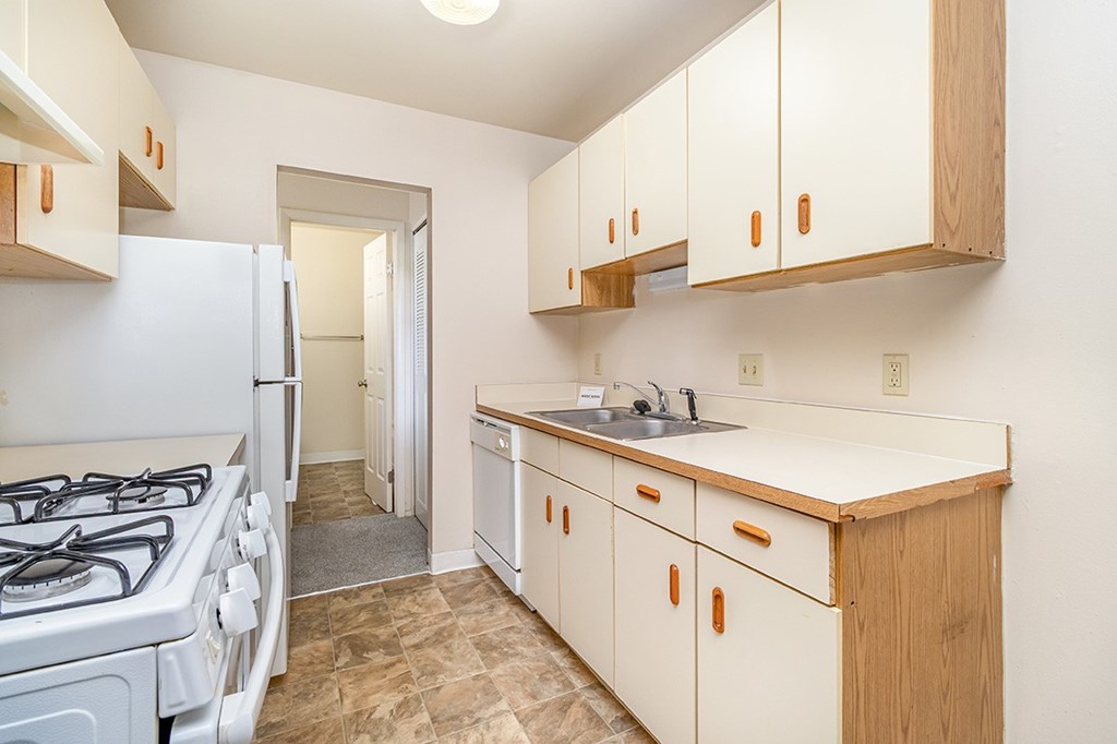 A galley style kitchen with a white gas stove and dishwasher at Mount Royal Townhomes, Michigan