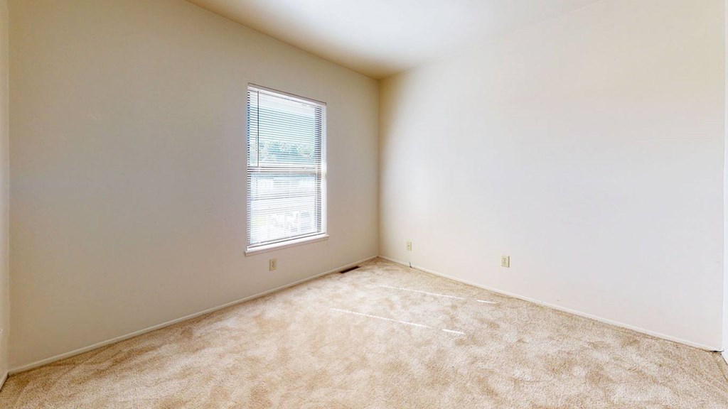 A bedroom with a window and carpeted floor at Mount Royal Townhomes, Kalamazoo, MI