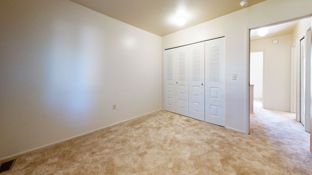 A bedroom with a carpeted floor and a closet at Mount Royal Townhomes, Kalamazoo, MI
