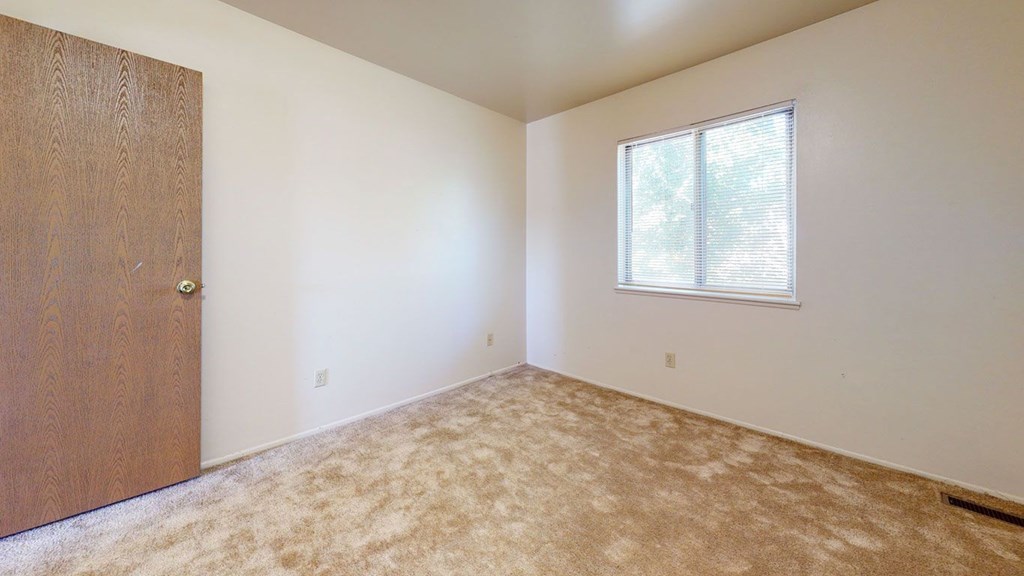 A bright bedroom with a window with blinds at Mount Royal Townhomes, Kalamazoo, MI