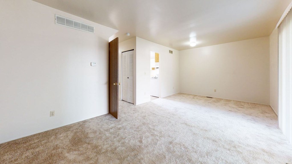 A living and dining room with a carpeted floor at Mount Royal Townhomes, Kalamazoo, MI