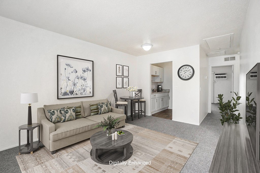 A living room with a couch, coffee table, and a painting on the wall at Newport Village Apartments, Portage, MI