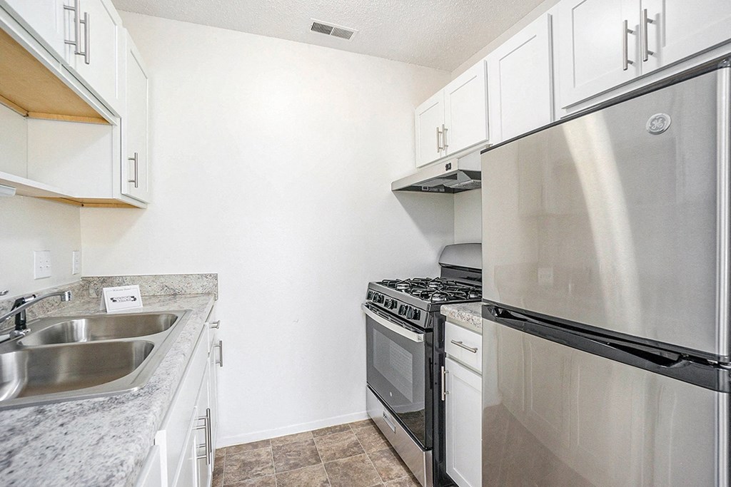 An upgraded kitchen with a stainless steel refrigerator and gas stove at Newport Village Apartments, Portage, MI
