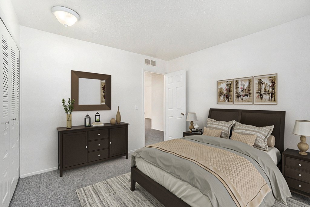 A bedroom with a bed, dresser, and mirror at Newport Village Apartments in Portage, MI