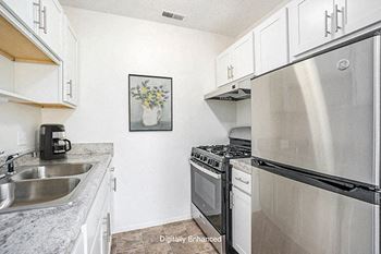 a kitchen with white cabinets and a gas stove Newport Village Apartments in Portage, MI 49002