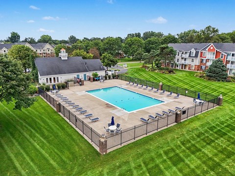 A pool surrounded by a fence and lawn chairs.