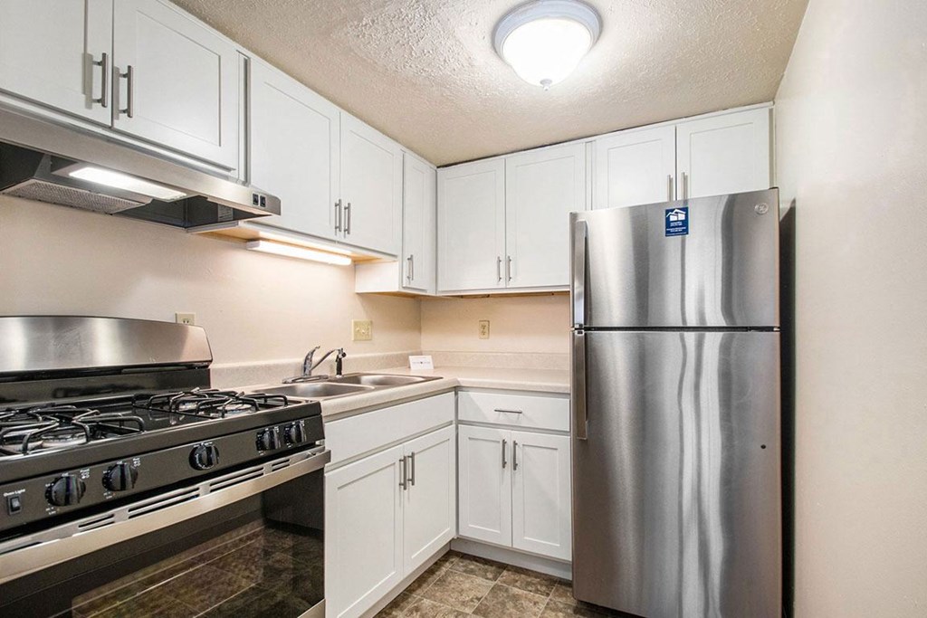 A kitchen with white cabinets and stainless steel appliances at Normandy Village Apartments, Michigan City