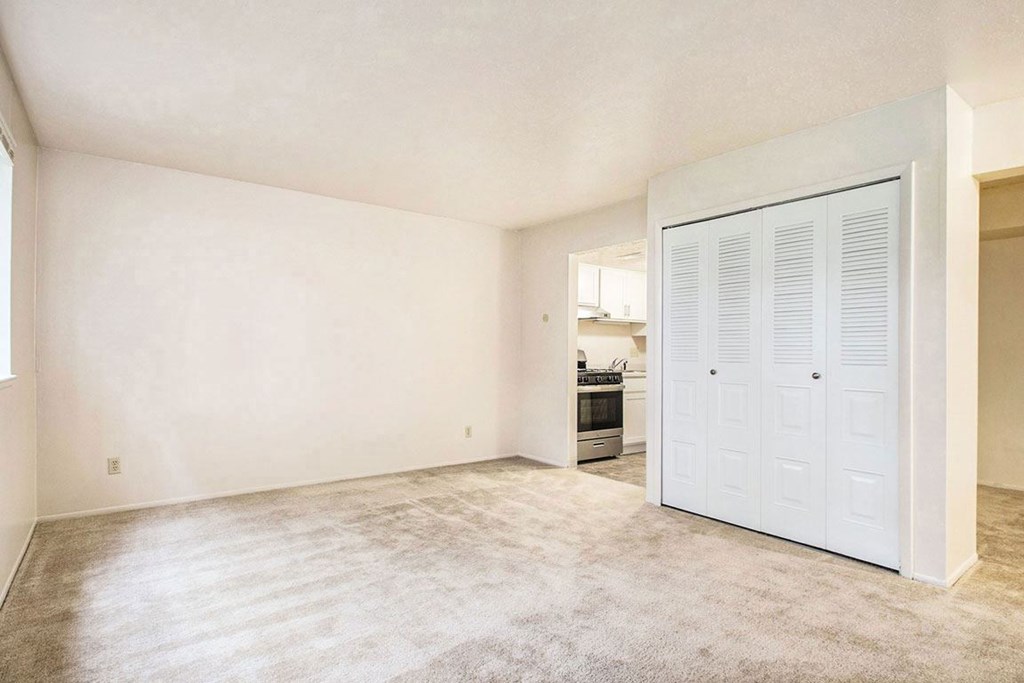 A living and dining area with a closet and a view of the kitchen at Normandy Village Apartments, Michigan City