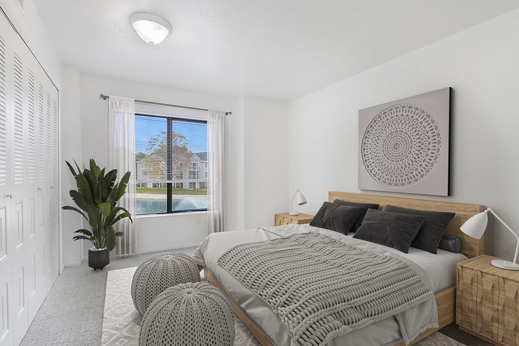 A bedroom with a large bed and a large window with a view at North Pointe Apartments, Elkhart