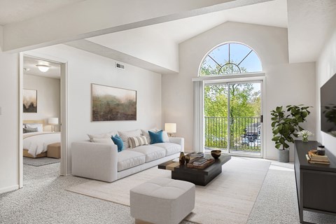A living room with a large window and a painting on the wall.