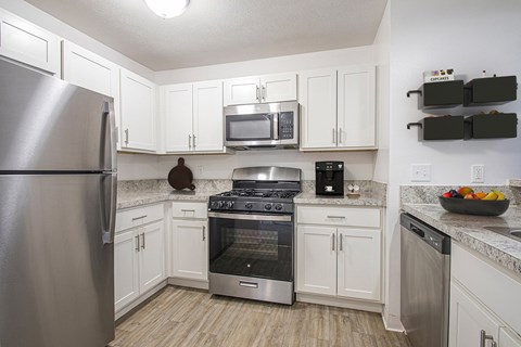 A kitchen with white cabinets and stainless steel appliances at Oak Shores Apartments in Oak Creek, WI