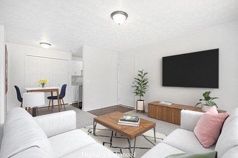 A modern living room with a white couch, a wooden coffee table, and a TV at Old Farm Apartments, Elkhart, Indiana