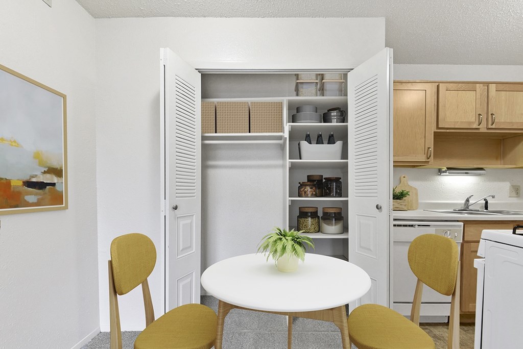 A kitchen and dining room with a large closet with shelves at Old Monterey Apartments in Springfield, MO