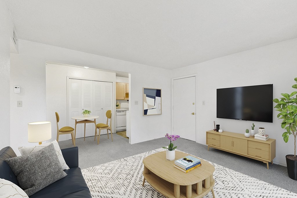 A living room with a grey couch, a wooden coffee table, and a flat screen TV on the wall at Old Monterey Apartments in Springfield, MO